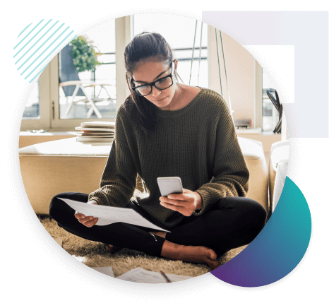 woman sat on floor reading papers and looking at her phone